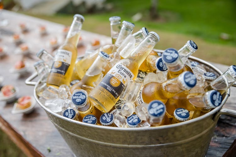 A Clear Coronita Extra Bottles Full Of Ice In Gray Steel Bucket