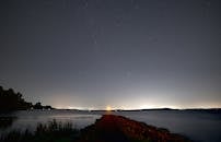 湖畔小径宁静，星空遍布，远处灯光闪烁，非常适合自然和旅行主题