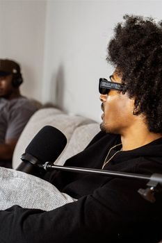 Close-up of an Afro-American man with a microphone in a podcast studio setting.