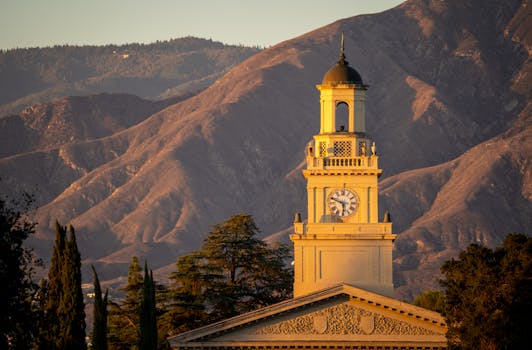 Clock tower in Redlands, CA with mountainous backdrop and warm sunset lighting.
