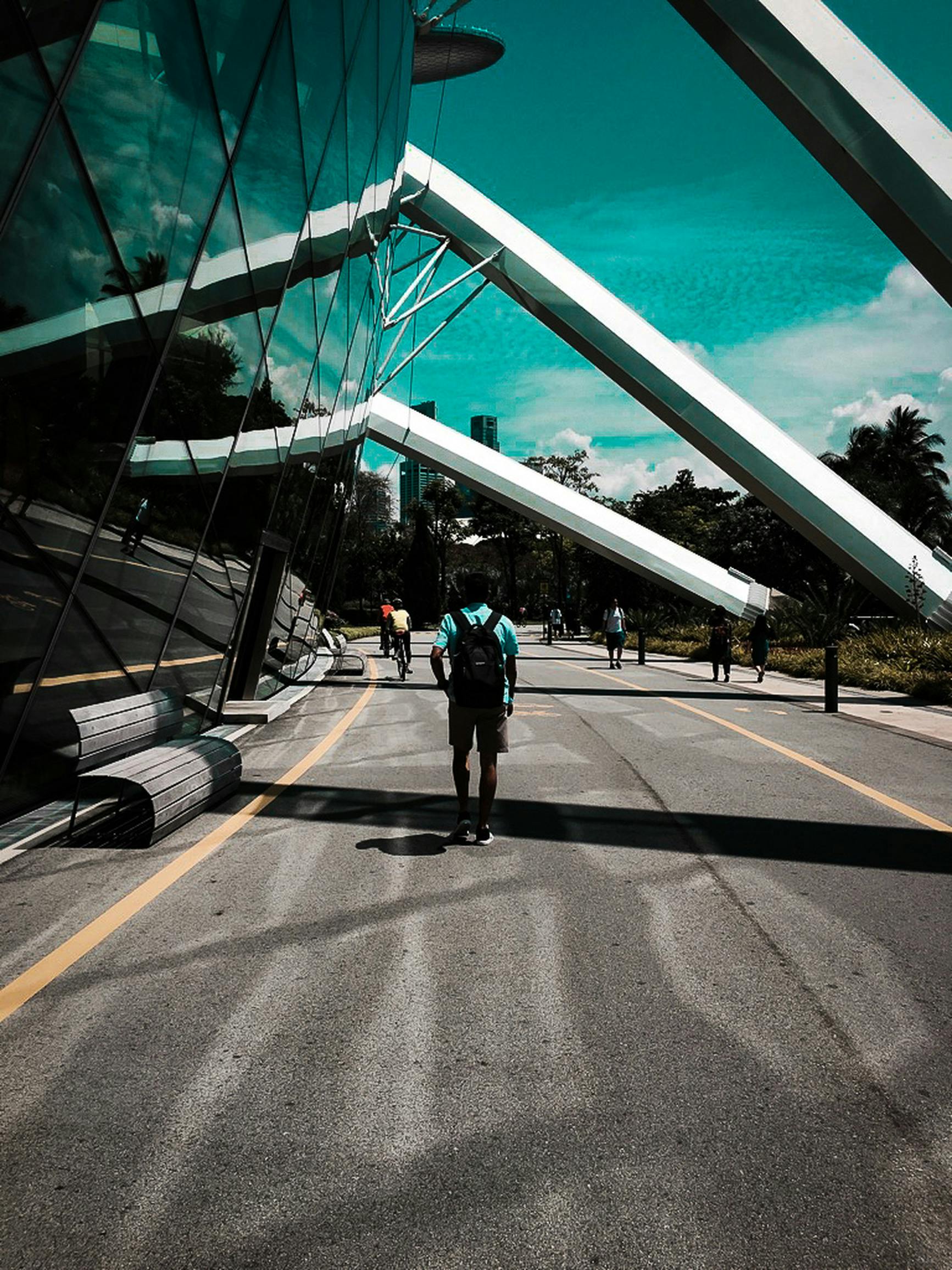 晴朗的天空下，行人行走在现代玻璃建筑构成的城市景观中