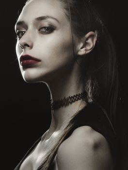 Dramatic portrait of a woman with red lipstick and choker, captured in a studio setting.