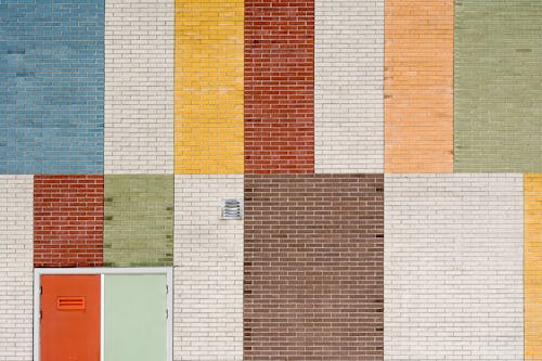 Free An Orange Door on Colorful Brick Wall  Stock Photo