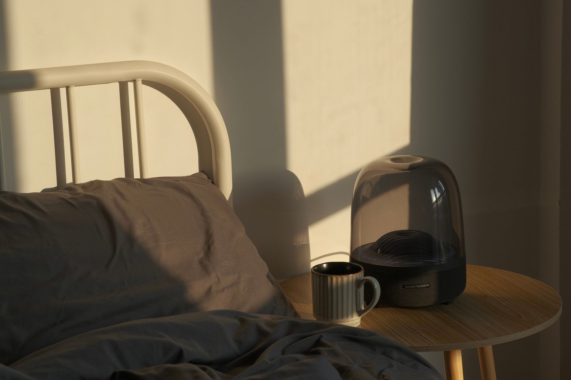 A serene bedroom scene with soft light, a mug, and modern decor for a cozy start to the day.