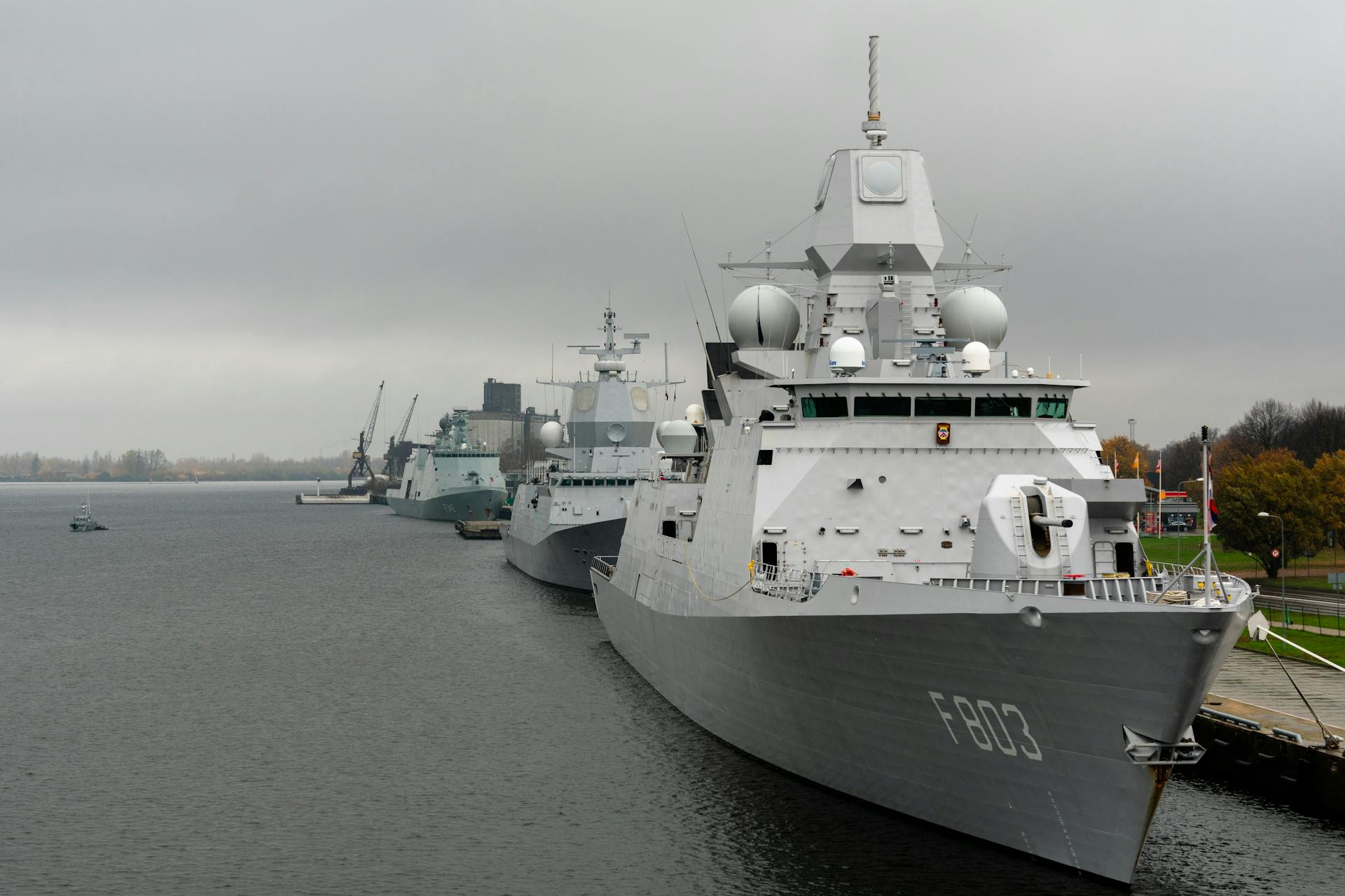 Moored warships at a harbor under cloudy skies, showcasing naval technology.