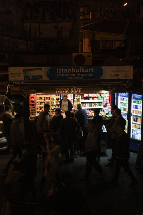 Free People gather around a bustling Istanbul street vendor at night, lit by shop lights. Stock Photo