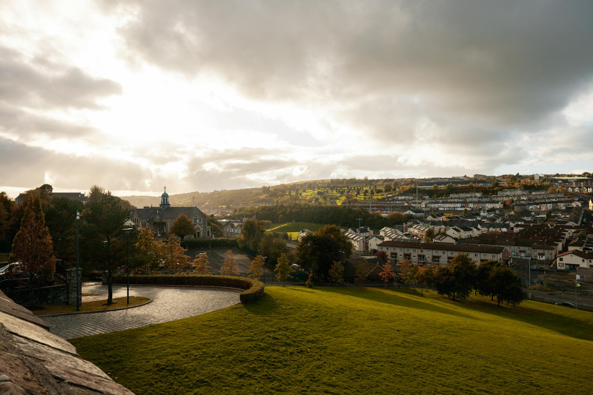 Charming Irish town with lush greenery and dramatic skies during sunset.