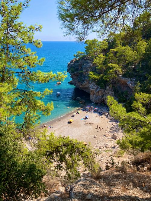Free Idyllic beach cove framed by rocky cliffs and turquoise sea, perfect for summer getaways. Stock Photo