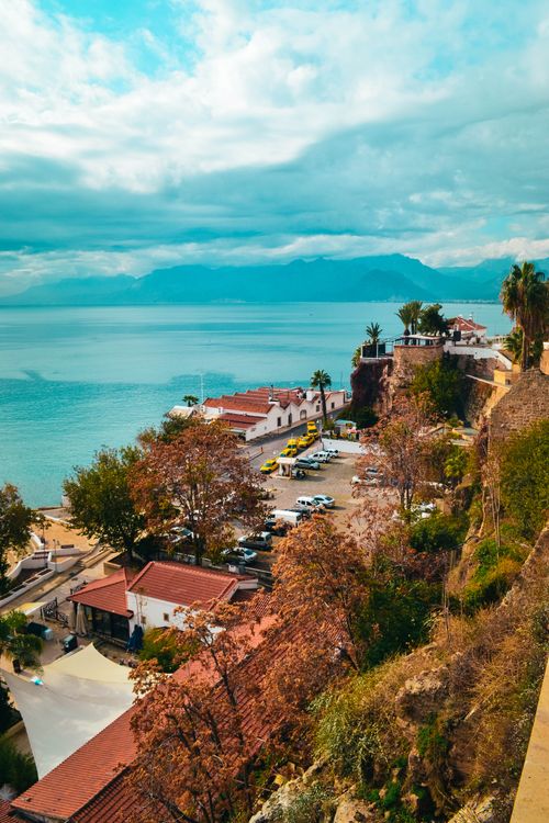 Free A vibrant coastal town scene with cliffs, buildings, and seascape under a cloudy sky. Stock Photo