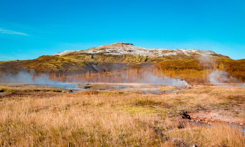 Brown Grass Field near the Mountain under Blue Sky