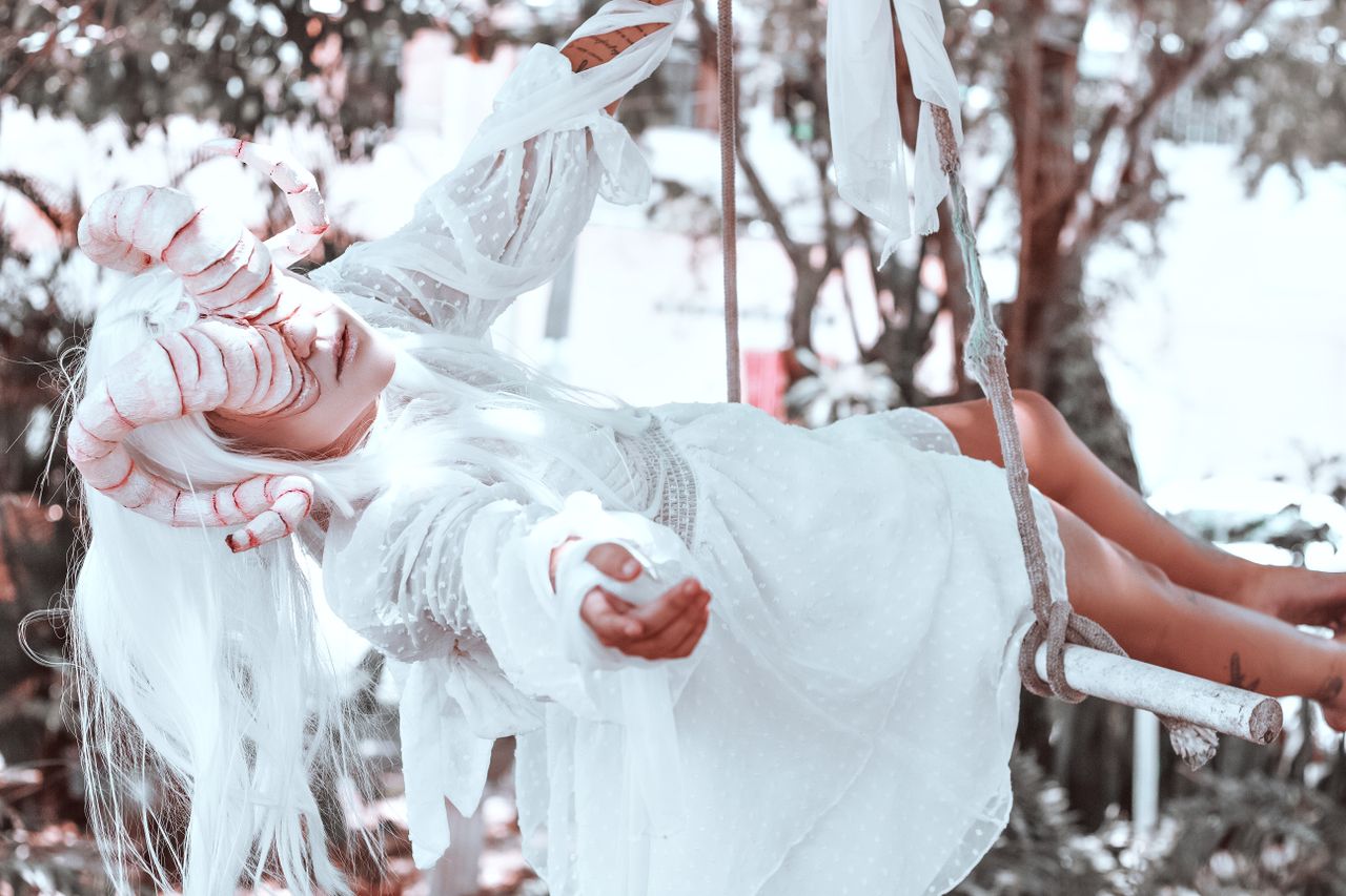 a person in a horned costume swings outdoors evoking a surreal fantasy