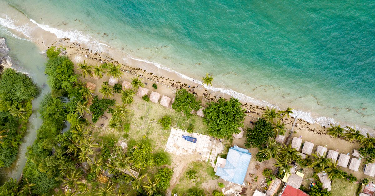 Aerial view of a tropical island beach resort with palm trees along the coastline