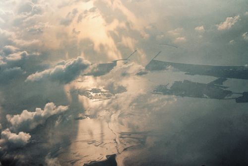 Free Captivating aerial view of clouds and a glistening water body with sunlight reflections. Stock Photo