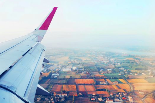 Scenic aerial view of sprawling farmland from an airplane window during daytime flight.