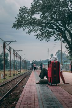Senior adult with suitcase sitting on a railway platform in Kurigram, Bangladesh.