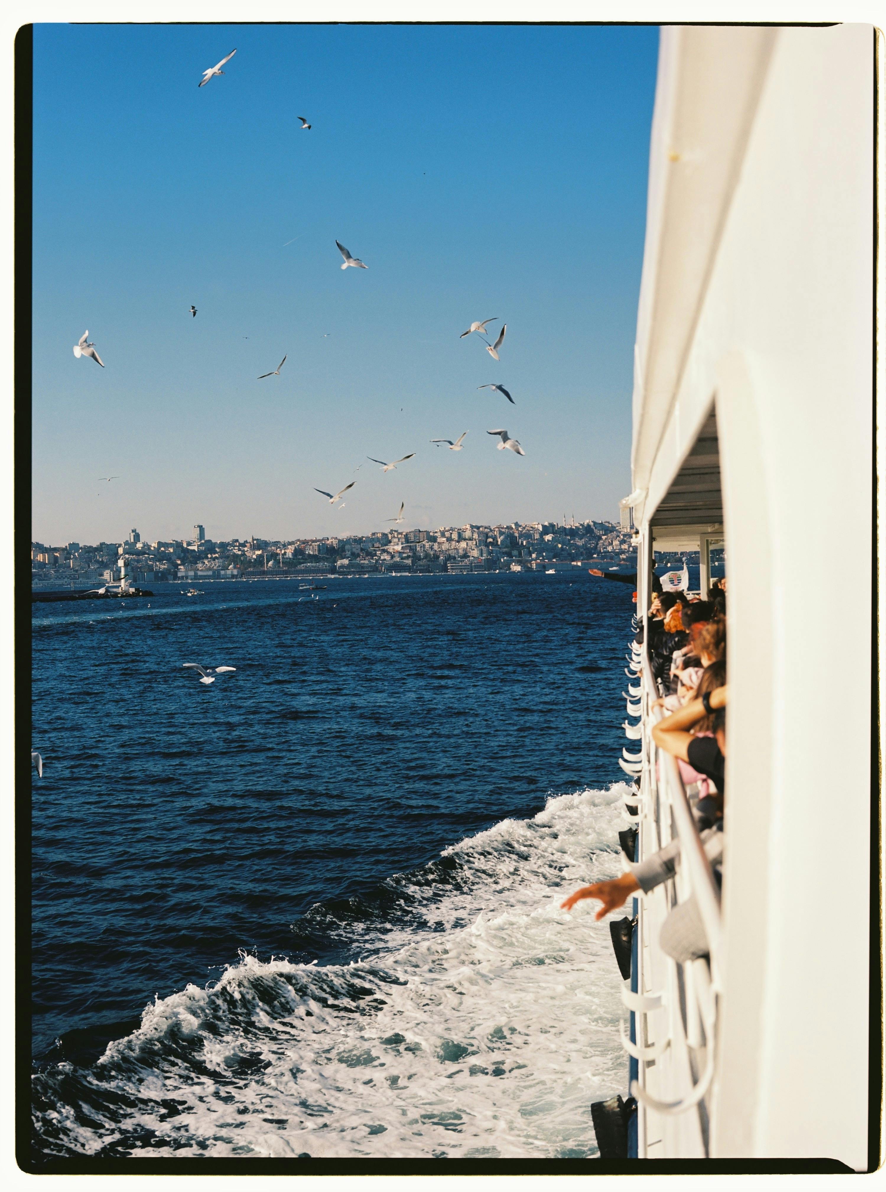 Passengers enjoy a ferry ride across the Bosphorus Strait in Istanbul under a clear blue sky.