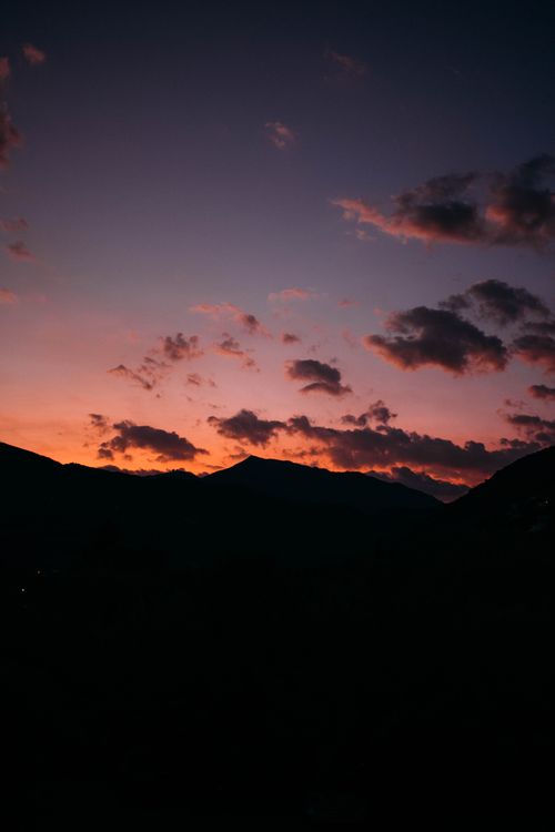 Free A stunning sunset with vibrant colors and mountain silhouettes creating a dramatic landscape. Stock Photo