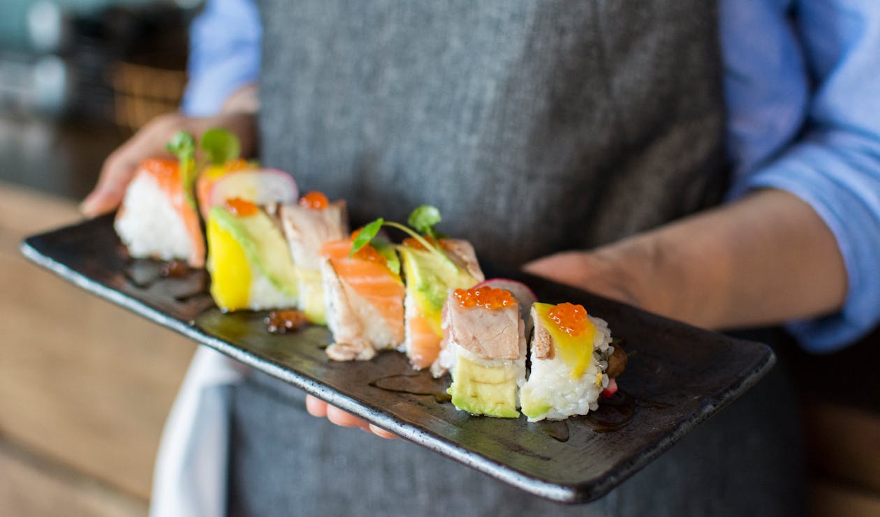 Free Person Holding Sushi on Black Plate Stock Photo