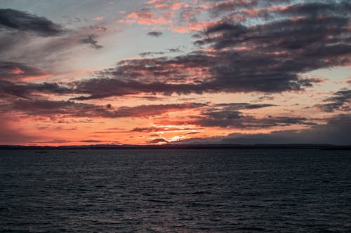 Free Body of Water Under Cloudy Sky during Sunset Stock Photo