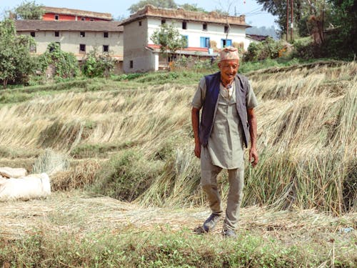 Elderly Man Walking on a Grass Field 