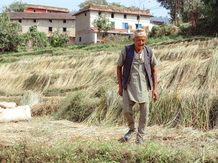 Elderly Man Walking On A Grass Field 