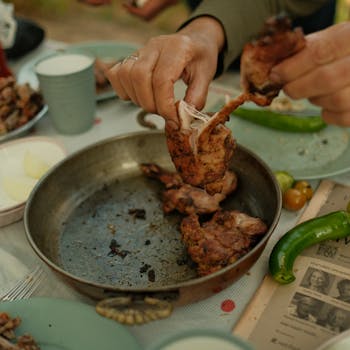 Delicious grilled chicken being shared at an outdoor meal setting, highlighting communal dining.