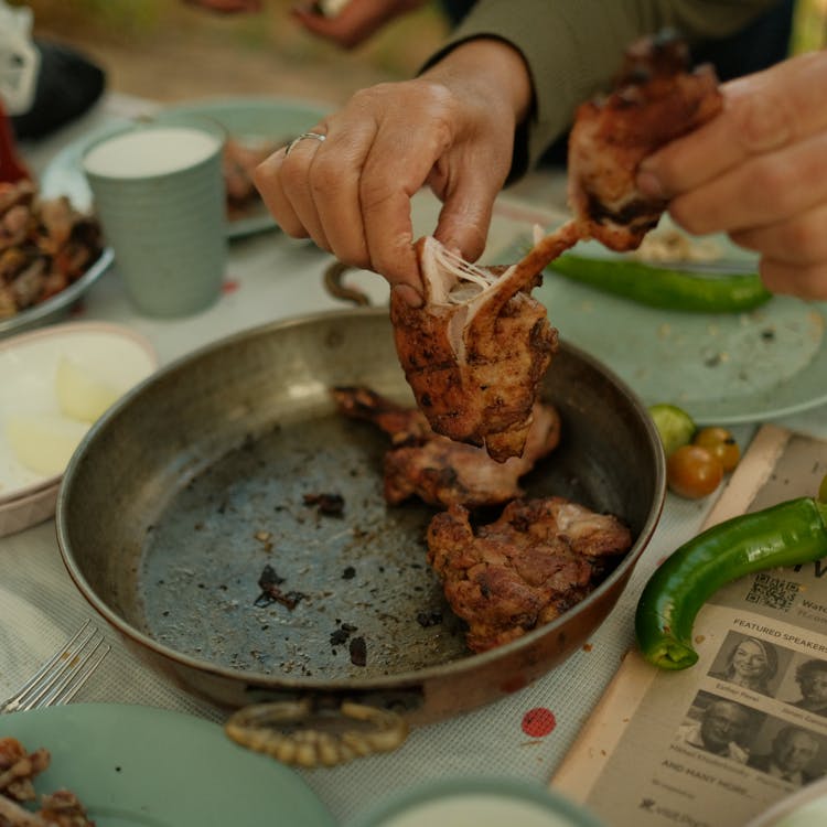 Close-up Of Person Taking Roasted Chicken From A Pan 