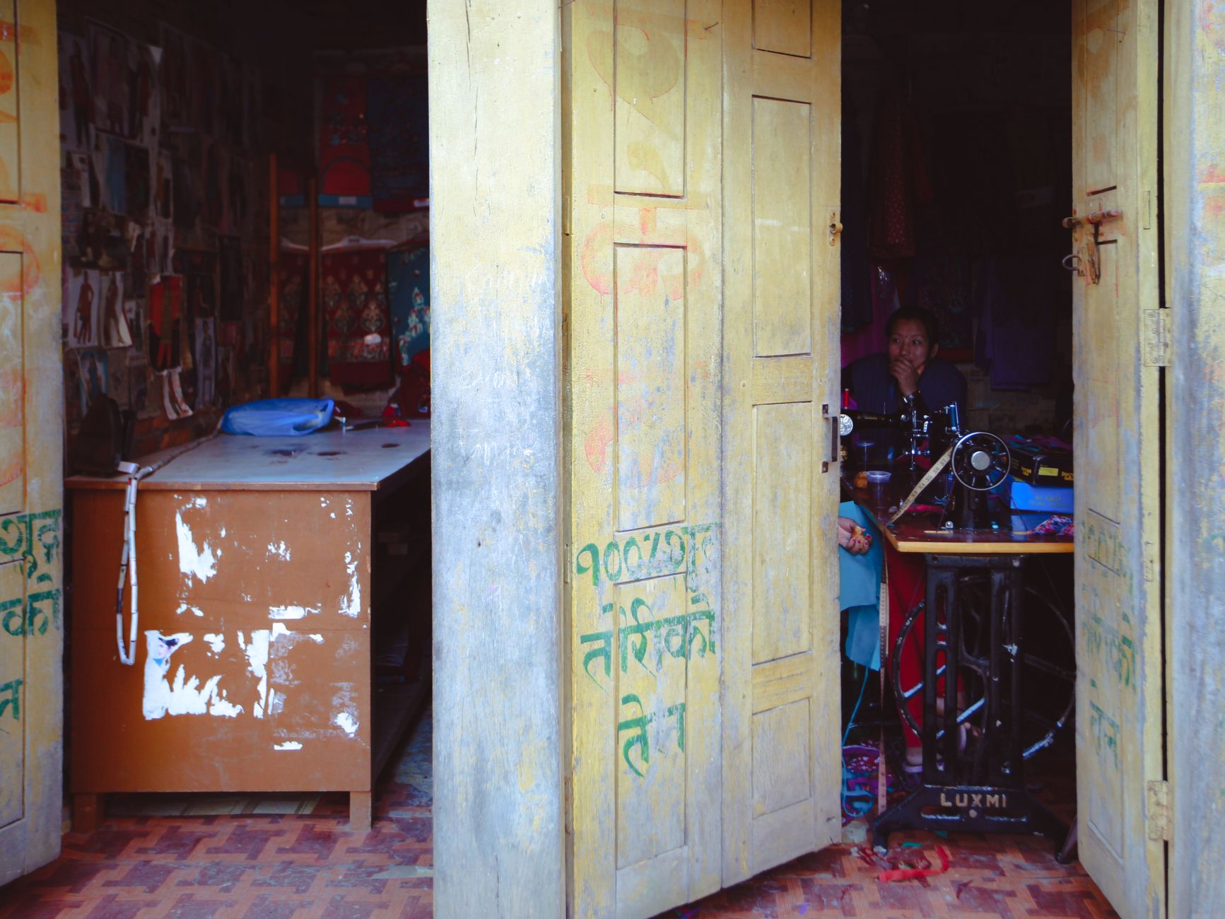 Open doorway revealing a traditional tailor shop with a sewing machine and colorful interiors.