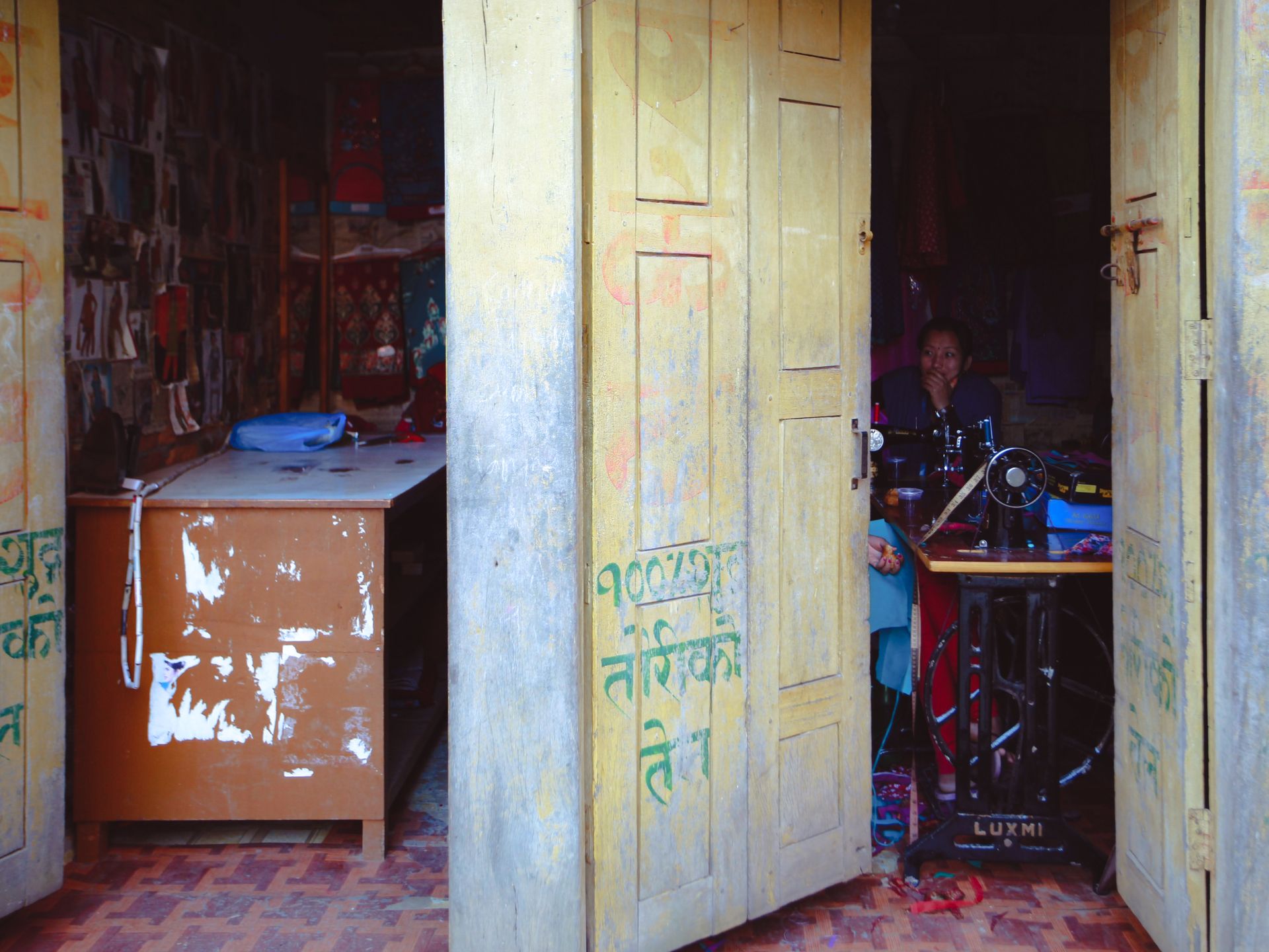 Open doorway revealing a traditional tailor shop with a sewing machine and colorful interiors.