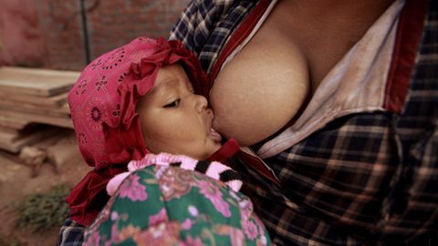 Close-up of a mother breastfeeding her baby outdoors, highlighting the bond and care.