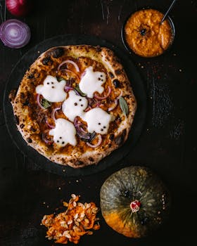 Spooky Halloween pizza topped with ghost-shaped cheese, surrounded by pumpkins and festive decor.