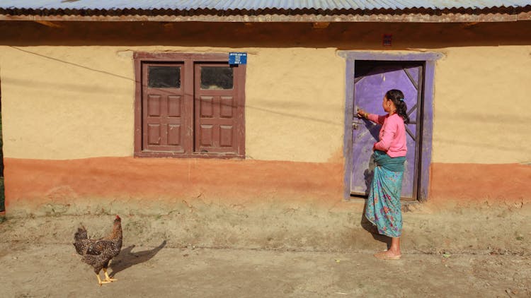 Woman And Hen In Yard In Front Of House