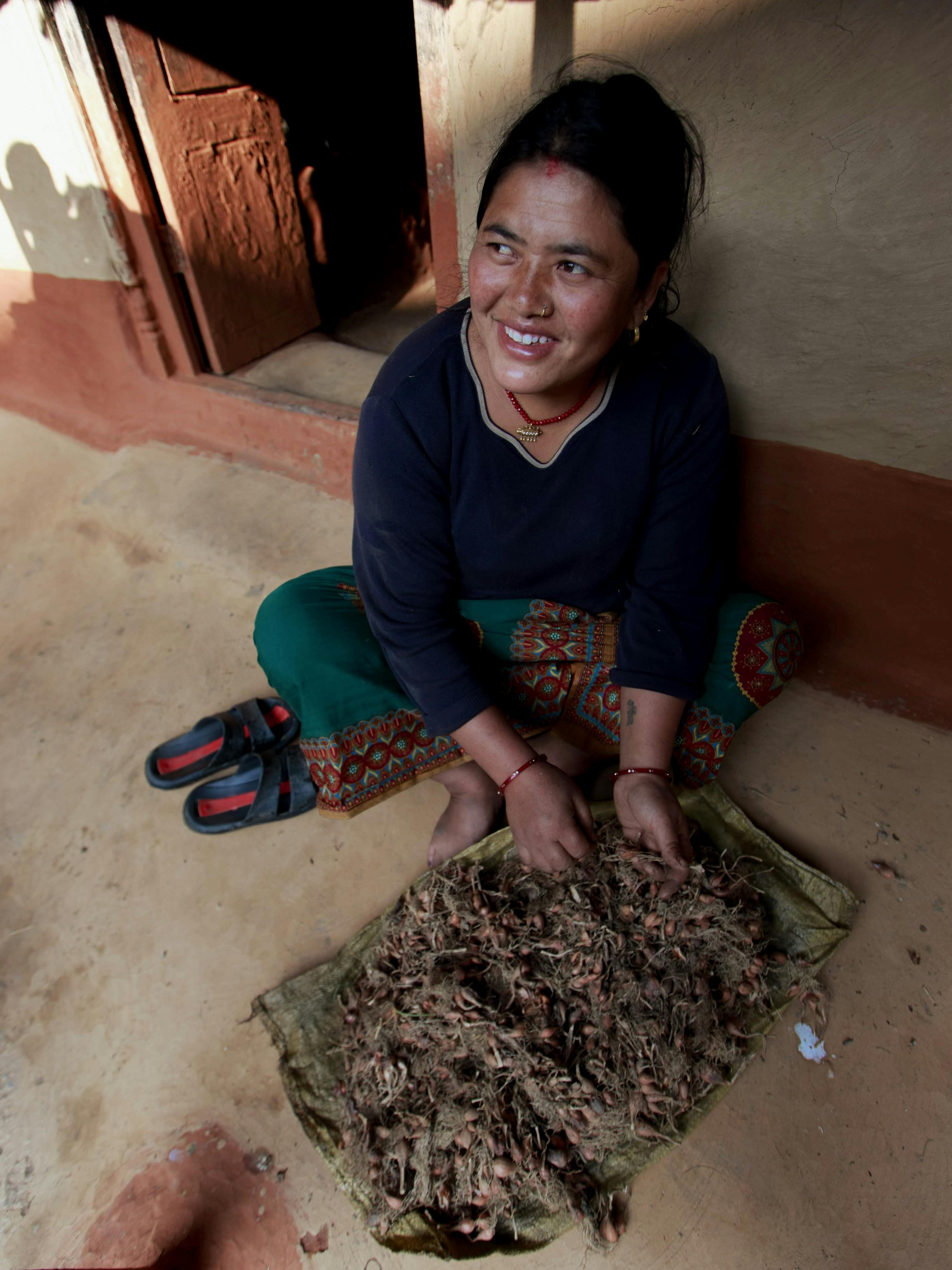 smiling woman sitting on the ground and cleaning tubers