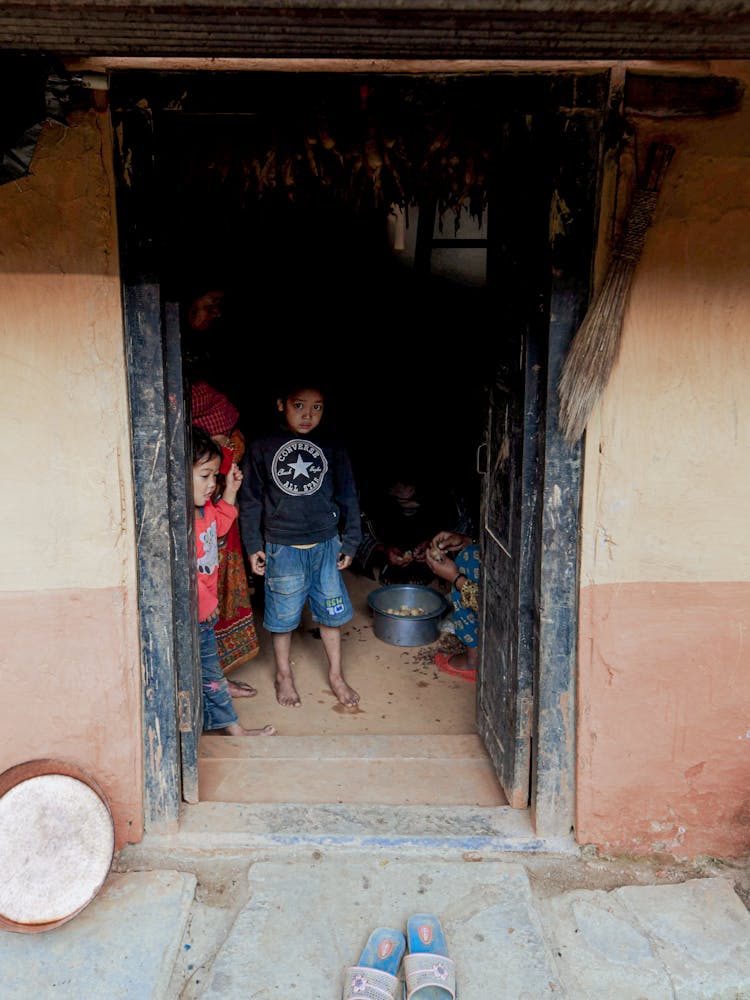 Children Standing In The Doorway To A House 