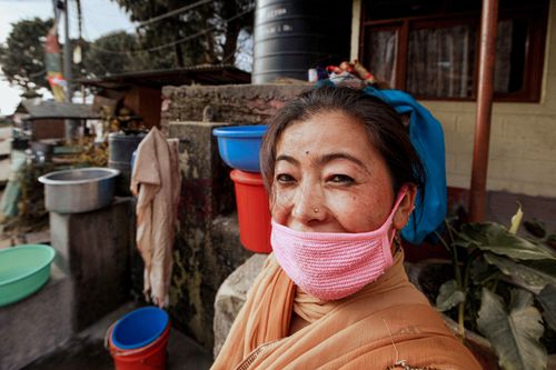 Free Close-up portrait of a woman wearing a pink face mask standing outdoors. Stock Photo