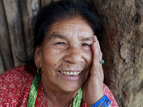 Free Close-up portrait of a joyful elderly woman with a nose ring and colorful attire. Stock Photo
