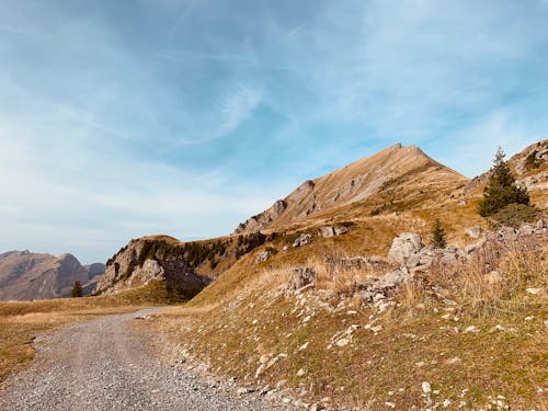 An Unpaved Pathway Near the Mountains Under the Cloudy Sky