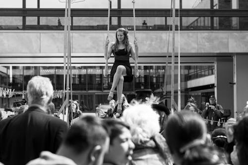 Greyscale Photography of a Crowd around Woman on Swing 