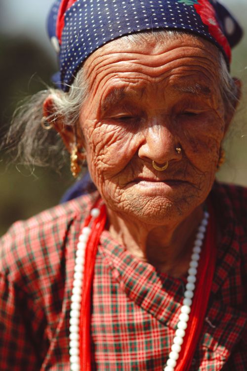 Free Close-up portrait of an elderly South Asian woman wearing traditional attire and jewelry, highlighting her wrinkles and nose piercing. Stock Photo