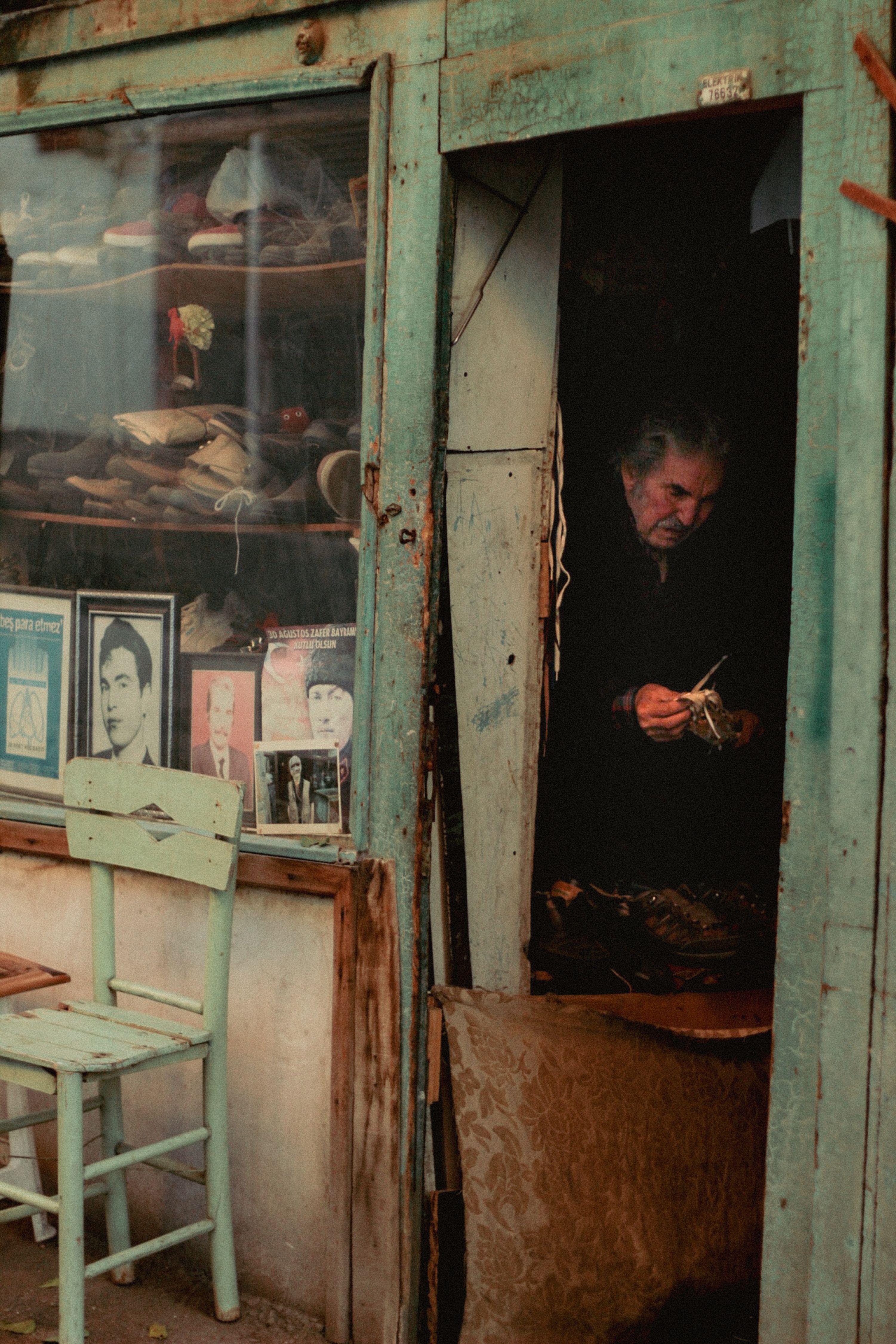 A charming, vintage storefront facade with an elderly man inside, surrounded by old photographs and items.