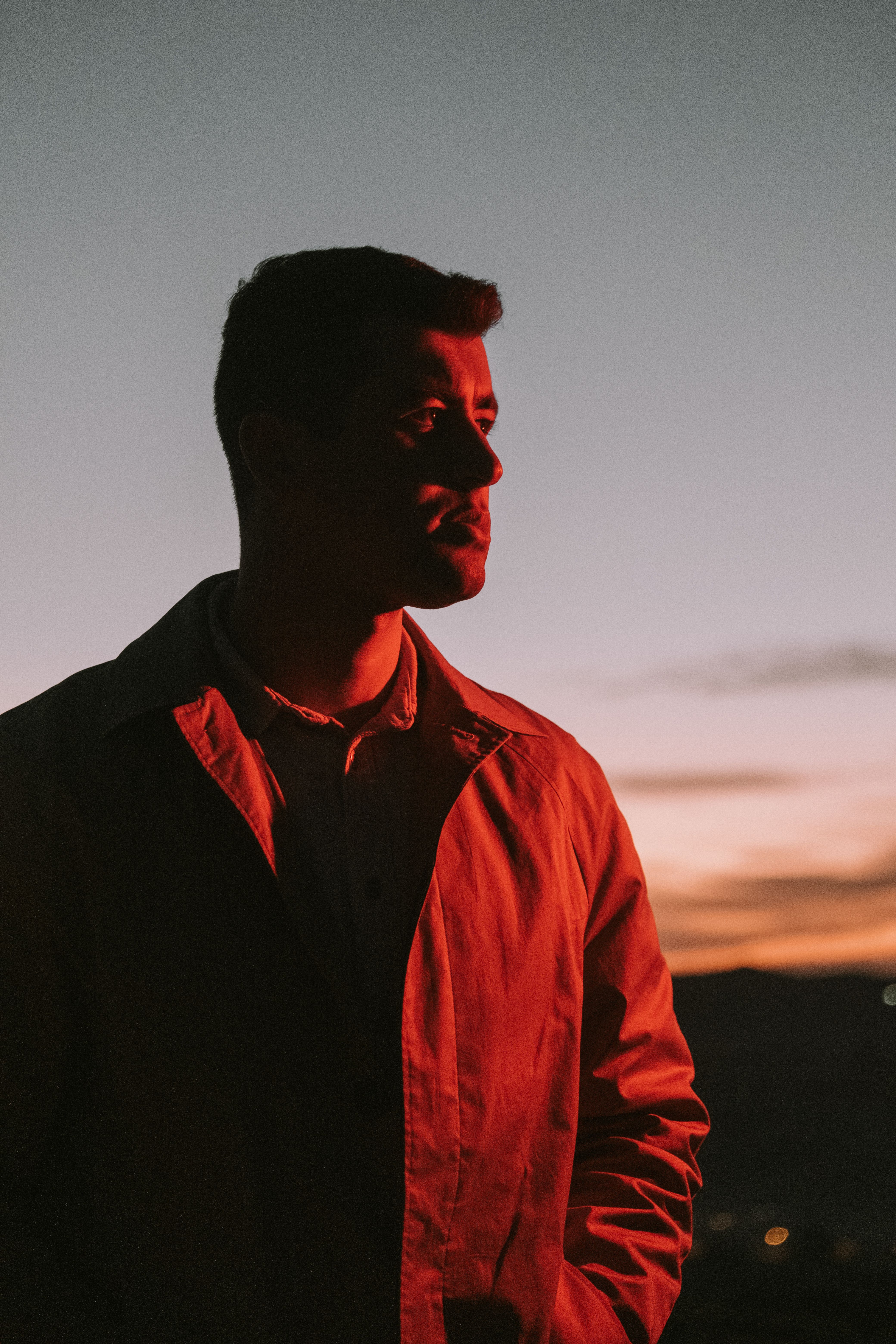 A man in a button-up shirt gazes into the sunset, creating a striking silhouette.