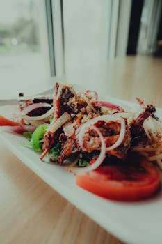 A beautifully plated Asian dish featuring crispy fried meat and fresh vegetables, perfect for a culinary experience.