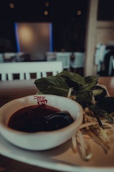 A cozy indoor Southeast Asian restaurant table with sauce and herbs on a plate capturing an inviting dining atmosphere.