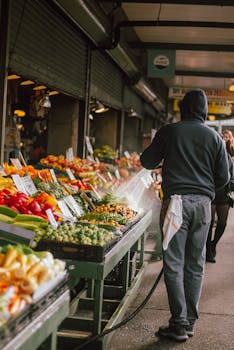 A vendor sprays fresh vegetables at an open market stall, keeping produce vibrant and inviting for shoppers.