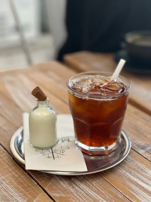 Free A glass of iced coffee served with cream on a wooden table, perfect for a caffeine boost. Stock Photo