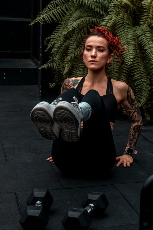 Free Tattooed woman with dyed hair performing workout indoors, emphasizing strength and fitness. Stock Photo
