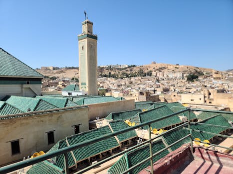 Aerial view of Fes with Kairaouine Mosque minaret under a clear blue sky.
