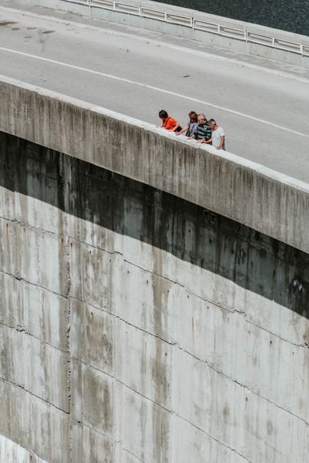 Group of people leaning over the edge of a concrete structure, exploring outdoors.