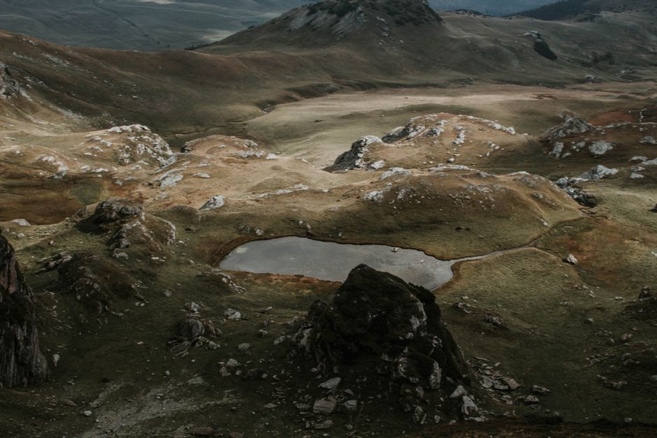Aerial view of rugged mountain landscape with a serene pond.