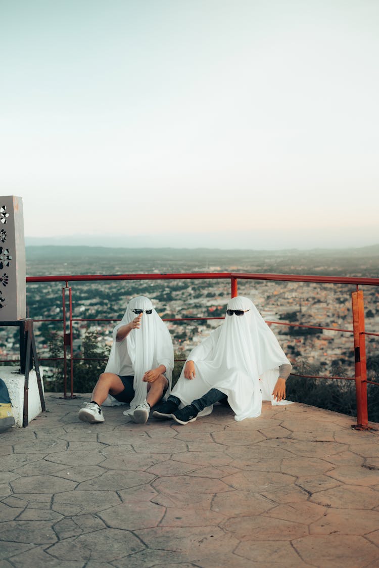 Men Sitting With White Veils On Heads And Sunglasses